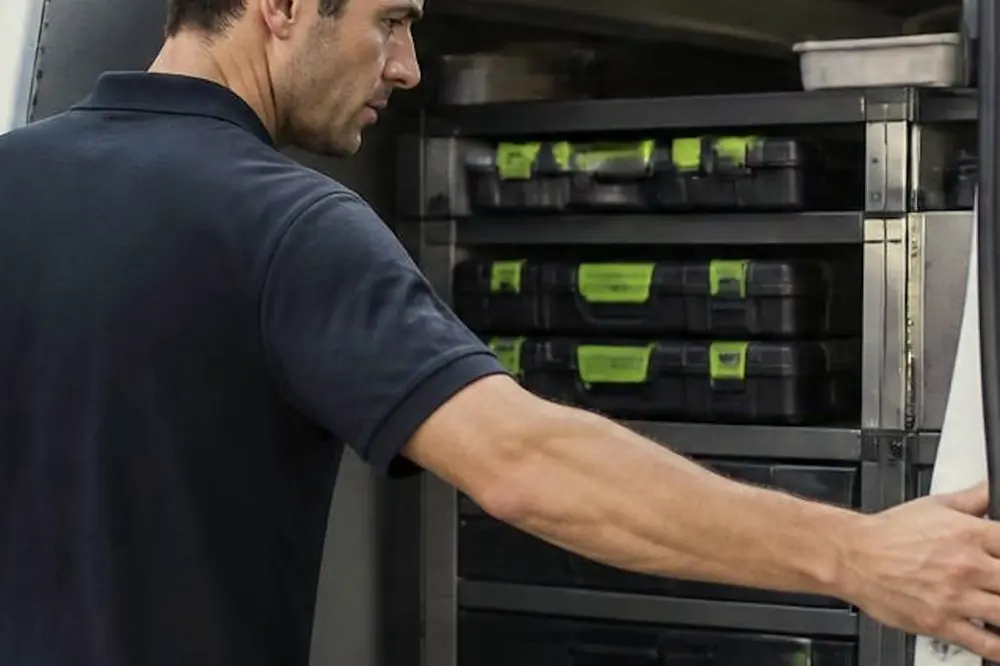 Technician at the open side of a service van with racks of parts cases
